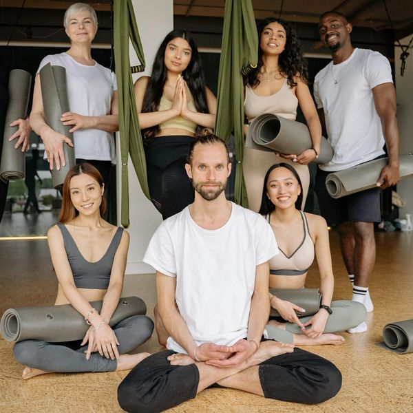 Group of diverse women smiling and sitting on yoga mats.